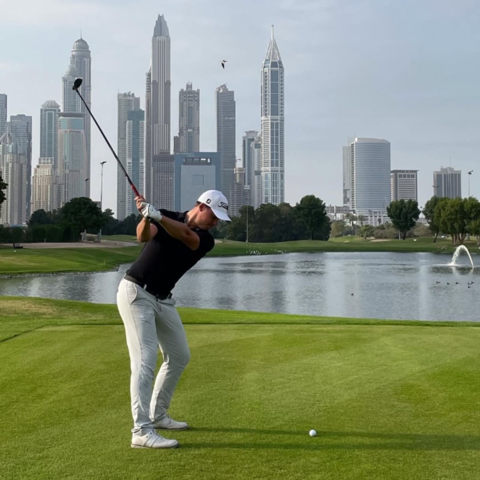 Belgian professional golfer Kristof Ulenaers playing golf internationally with the Dubai skyline in the background